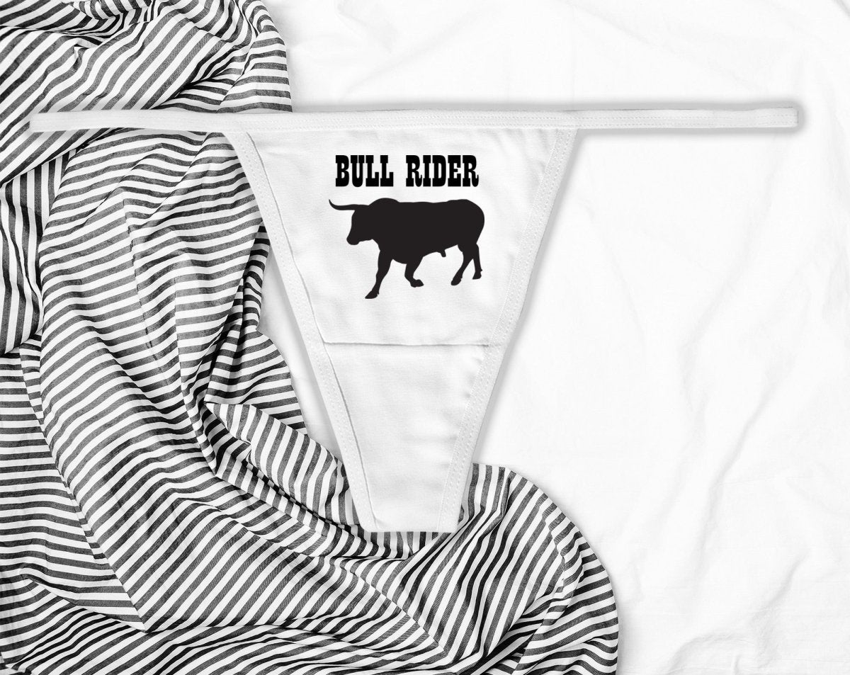 Sexy white thong with “Bull Rider” text in bold black print. Western-inspired lingerie for confident women who love to ride hard and dominate the scene.