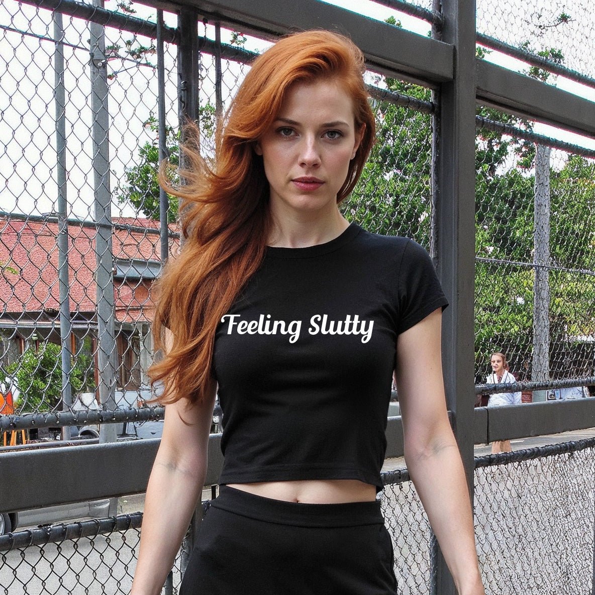 Redhead woman wearing a black crop top with “Feeling Slutty” in white text. Flirty kink shirt for bratty submissives and public play teasing.