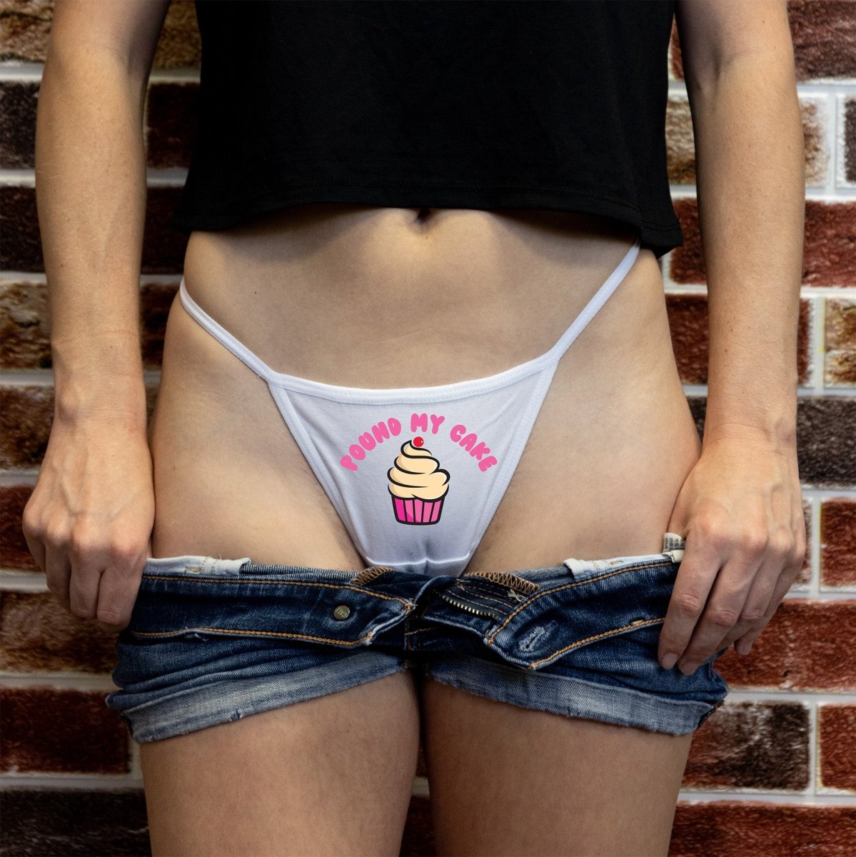 Blonde woman modeling “Pound My Cake” thong panty with cupcake graphic – naughty dessert-themed lingerie by Wicked Boutique.