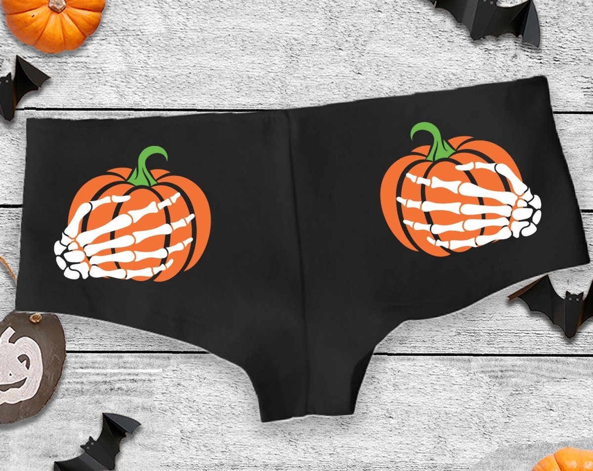 Black cheeky panties with orange pumpkin designs and white skeleton hands on each cheek.